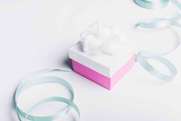 Satin ribbon with closed gift box on white background