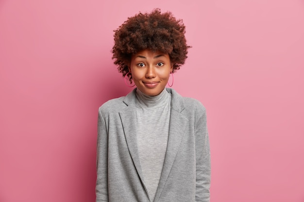 Satisfied African American woman in grey formal clothes feels happy