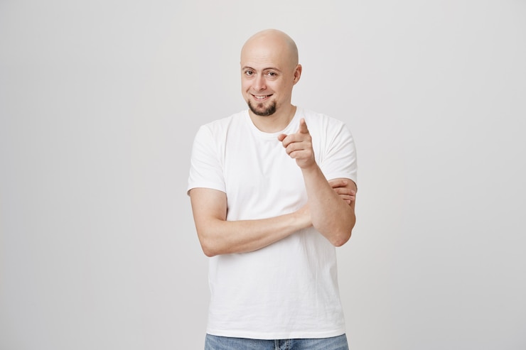 Free Photo satisfied bald guy pointing at front, good point