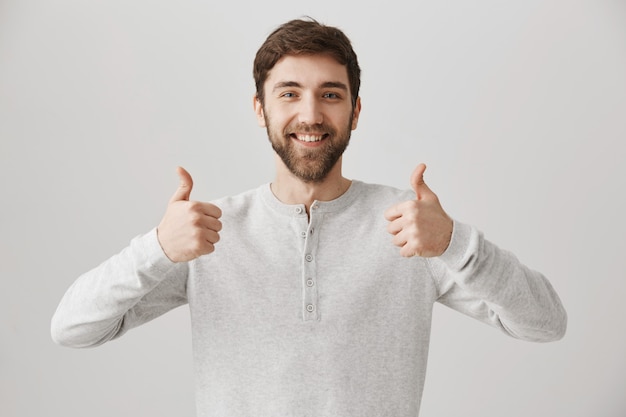 Free photo satisfied bearded male customer show thumbs-up in approval