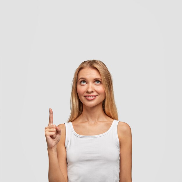 Satisfied blonde woman with long hair, points her finger