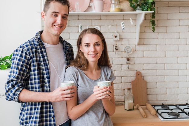 Satisfied bonding couple resting in kitchen and sipping brew 