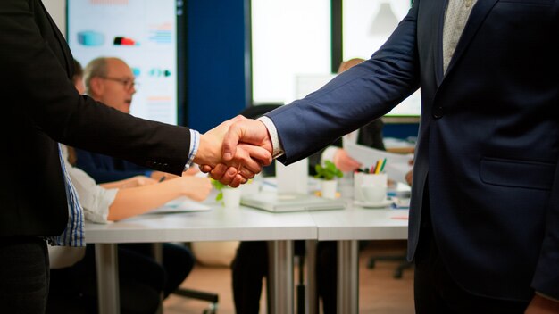 Satisfied businessman company employer wearing suit handshake new employee get hired at job interview, male hr manager employ successful candidate shake hand at business meeting, placement concept