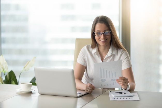 Satisfied businesswoman revising financial results