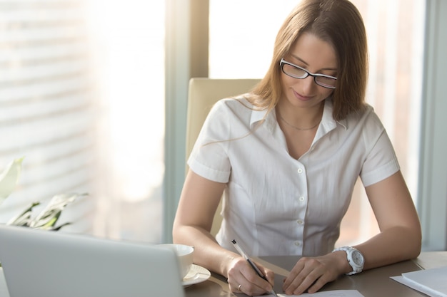 Satisfied businesswoman signs a contract at desk