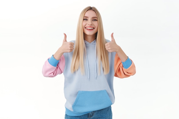 Free photo satisfied cheerful, attractive blonde girl show thumbs-up in like or approval