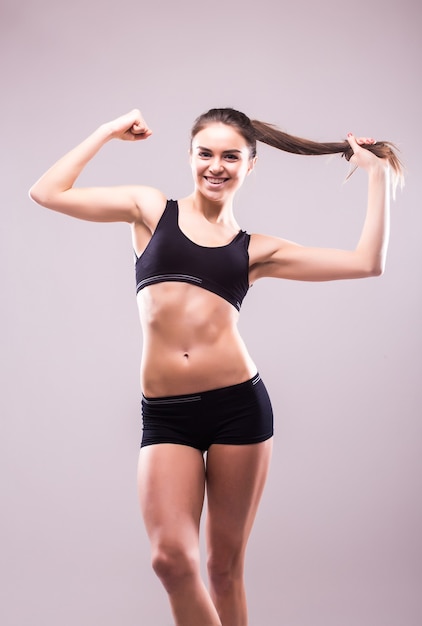Довольная уверенно активная здоровая женщина в спортивной одежде с руками на бедрах