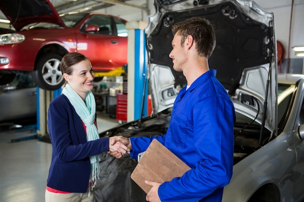 Satisfied customer shaking hands with mechanic