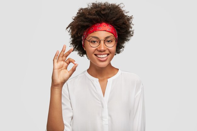 Satisfied ethnic female worker makes okay gesture, has work under control