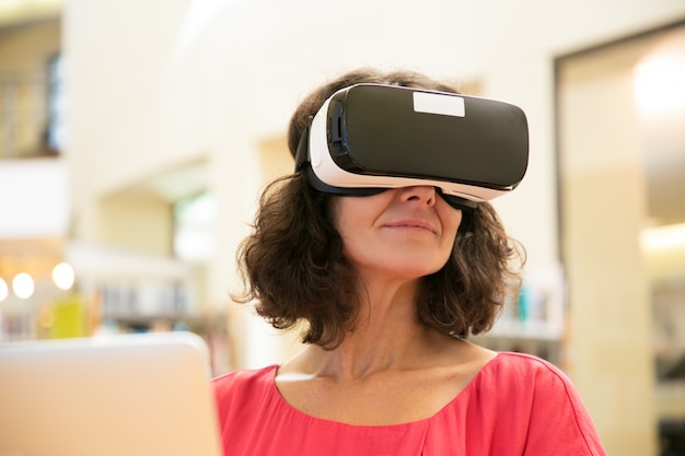 Free photo satisfied female gadget user enjoying vr experience