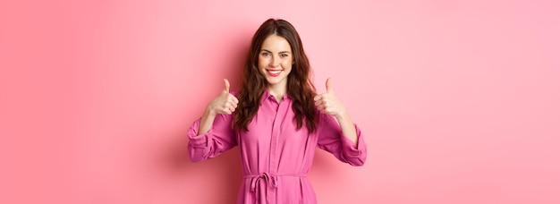Бесплатное фото Удовлетворенная женщина, показывающая большой палец вверх в знак одобрения, говорит 