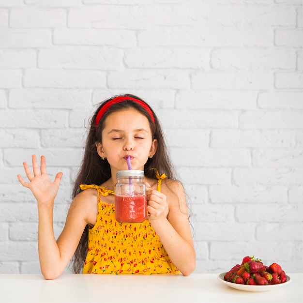 Foto gratuita ragazza soddisfatta che beve i frullati della fragola in barattolo