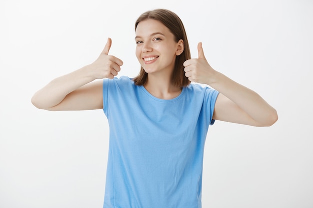 Satisfied good-looking woman smiling and showing thumbs-up in approval, guarantee quality