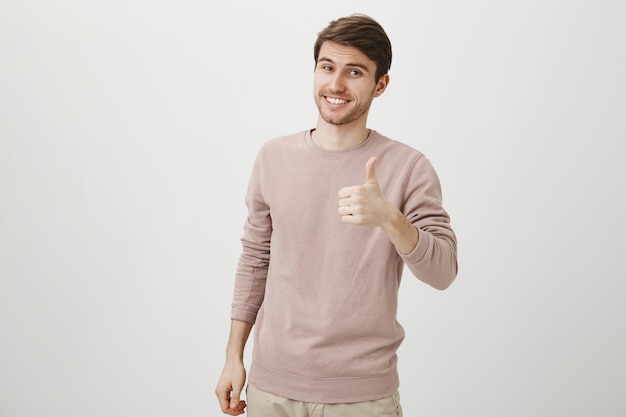 Free photo satisfied handsome caucasian man showing thumbs-up
