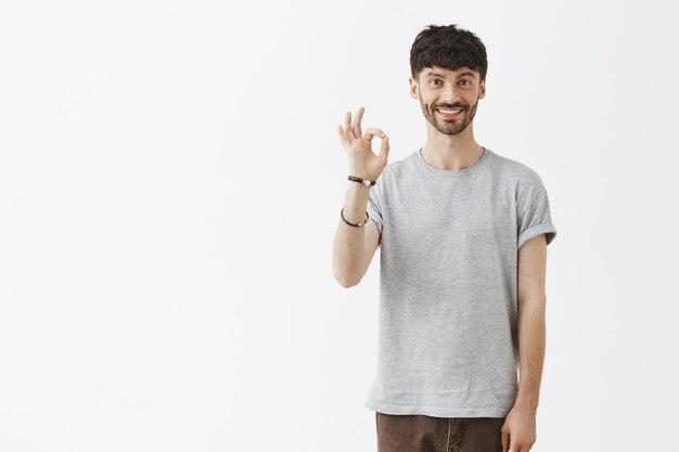 Satisfied handsome guy posing against the white wall