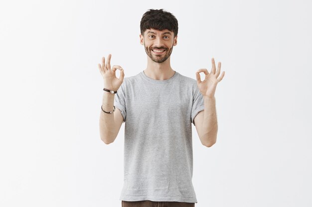 Satisfied handsome guy posing against the white wall