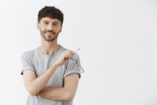 Free photo satisfied handsome guy posing against the white wall