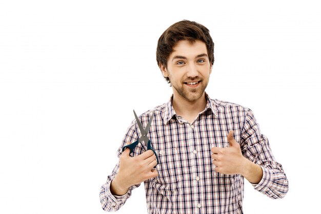 Satisfied handsome man, thumb-up, hold scissors