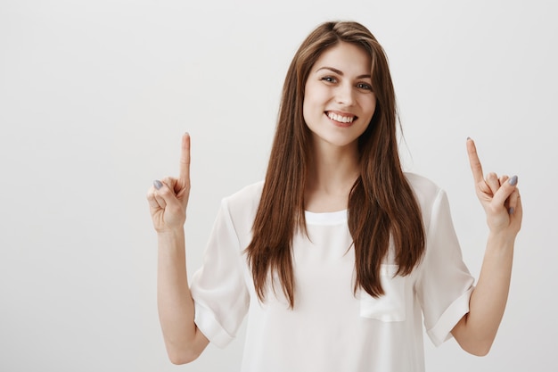 Ragazza graziosa felice soddisfatta che indica le barrette su e sorridere