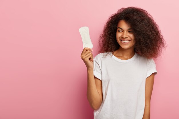 Satisfied lovely woman with crisp hairstyle, holds sanitary napkin