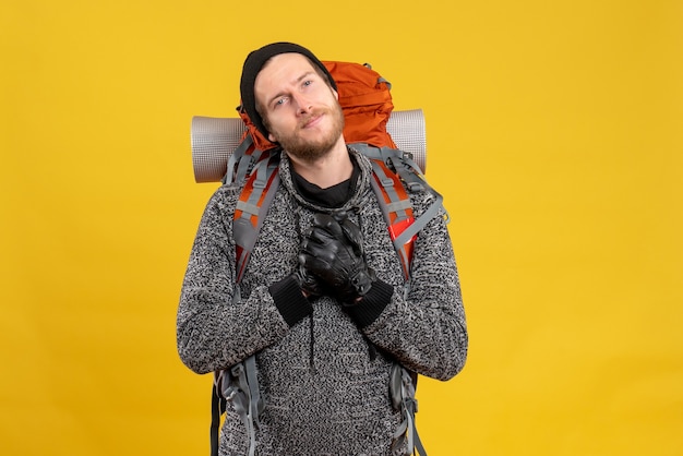 satisfied male hitchhiker with leather gloves and backpack putting hands on his chest