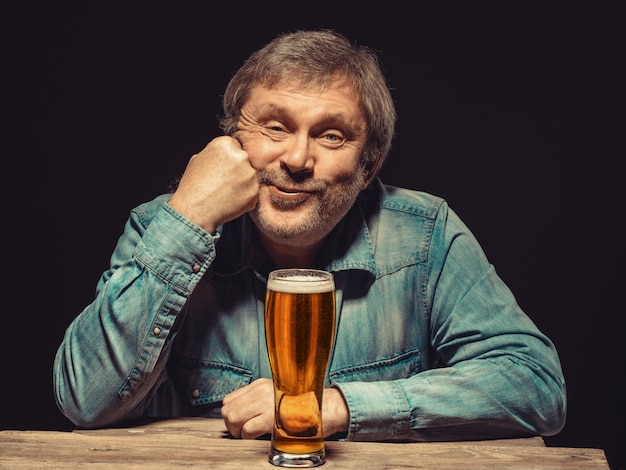 satisfied man in denim shirt with glass of beer