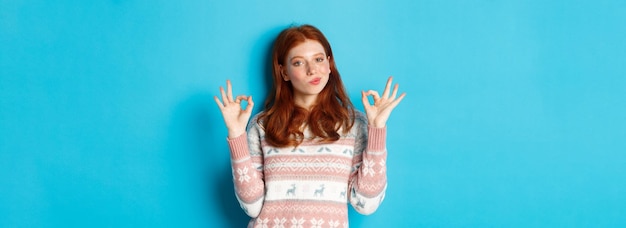 Free photo satisfied and proud redhead girl nod in approval showing okay sign not bad or praise gesture standin