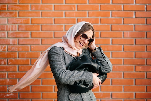 Satisfied young lady holding her handbag