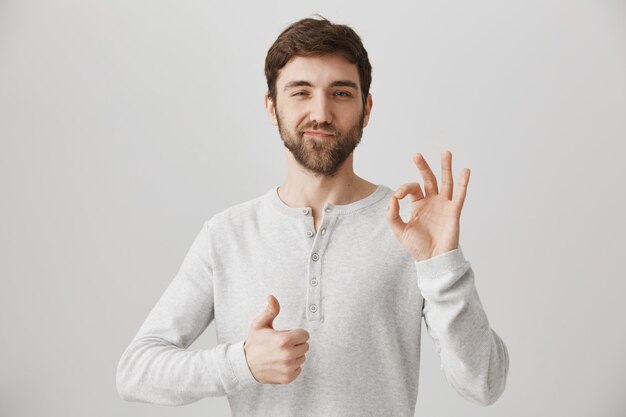 Satisfied young man show thumbs-up and okay sign