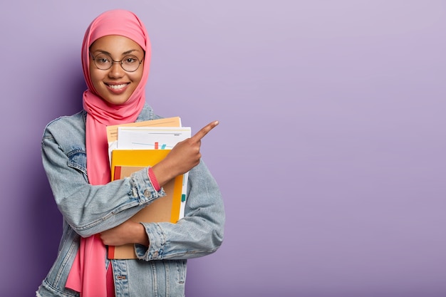 Foto gratuita studente universitario musulmano soddisfatto con blocco note e documenti