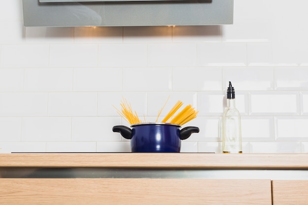 Saucepan on cooking table in kitchen with bottle of oil