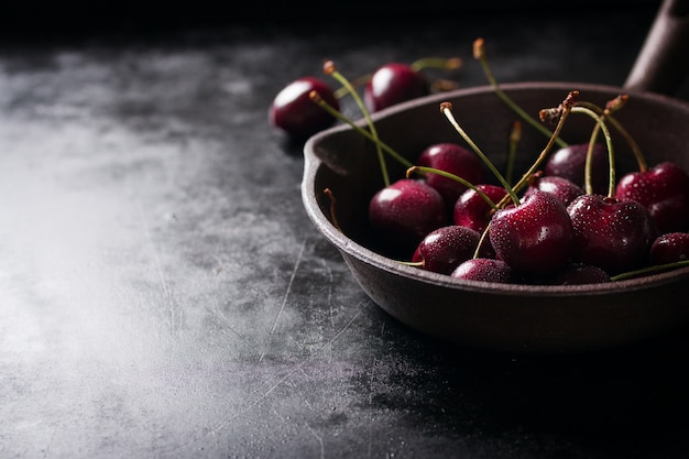 Saucepan with cherries on a black wooden table