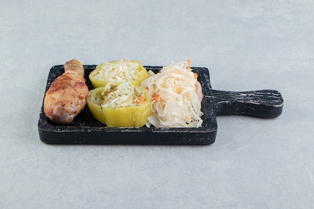 Sauerkraut and fried chicken leg on black board.  