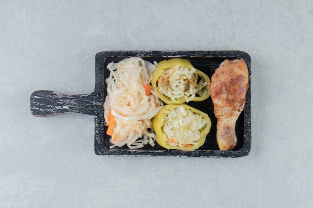 Sauerkraut and fried chicken leg on black board. 