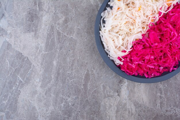 Sauerkraut and red cabbage on black wooden board.