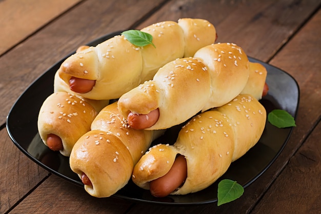 sausage in the dough sprinkled with sesame seeds on a wooden table in rustic style