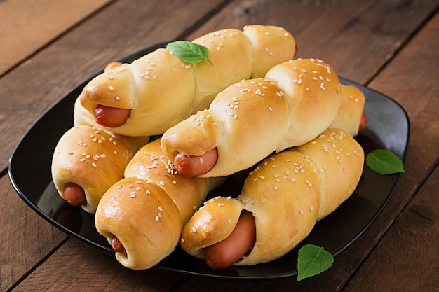 Free photo sausage in the dough sprinkled with sesame seeds on a wooden table in rustic style