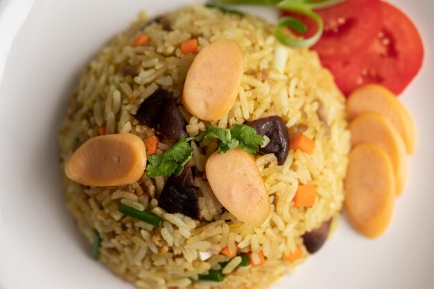 Колбаса жареный рис с помидорами, морковью и грибами шиитаке на тарелке