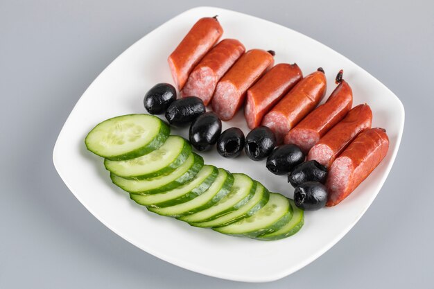 Sausage pieces with sliced cucumbers and black olives