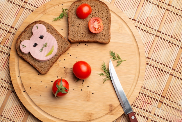 Колбаса с черным хлебом и помидорами на деревянном фоне Premium Фотографии