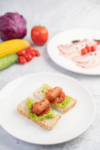 Sausage with tomatoes, salad and two sets of bread on a white plate.