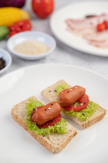 Sausage with tomatoes, salad and two sets of bread on a white plate.