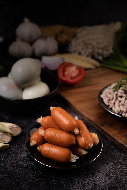 Sausages on a black plate that are placed on the cement floor