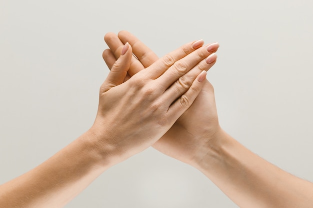 Say hello to the new meetings. Male and female hands demonstrating a gesture of getting touch or greetings isolated on gray studio background. Concept of human relations, relationship or business.