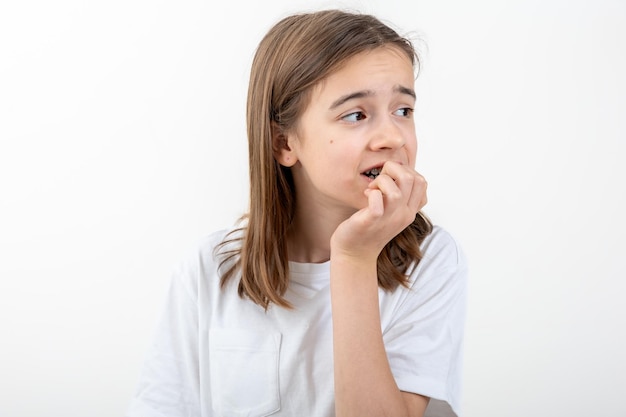 Scared and anxious girl biting her fingernails on a white background isolated