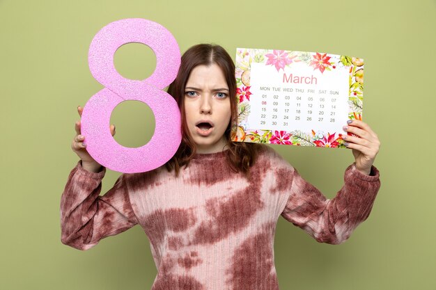 顔の周りのカレンダーで8番を保持している幸せな女性の日に怖い美しい少女