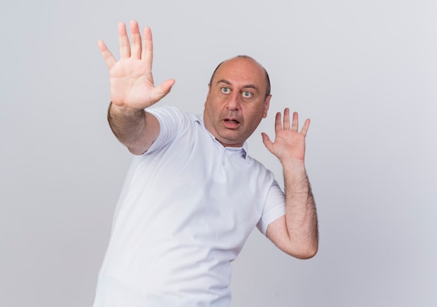 Scared casual mature businessman looking straight and stretching out hand and keeping another one in air gesturing no isolated on white background with copy space