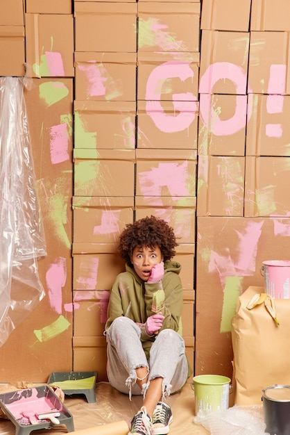 Scared emotional creative woman decorator sits on floor 