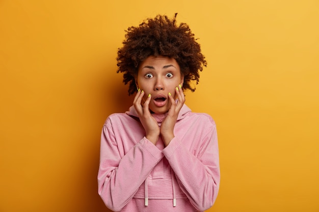 Scared emotional dark-skinned woman gasps from fear