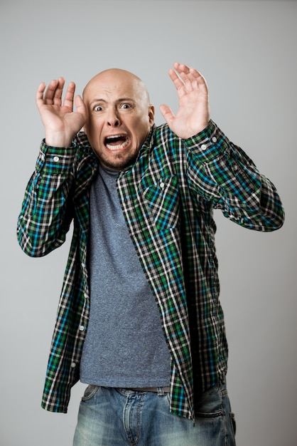 Free photo scared emotive young man shouting over beige wall